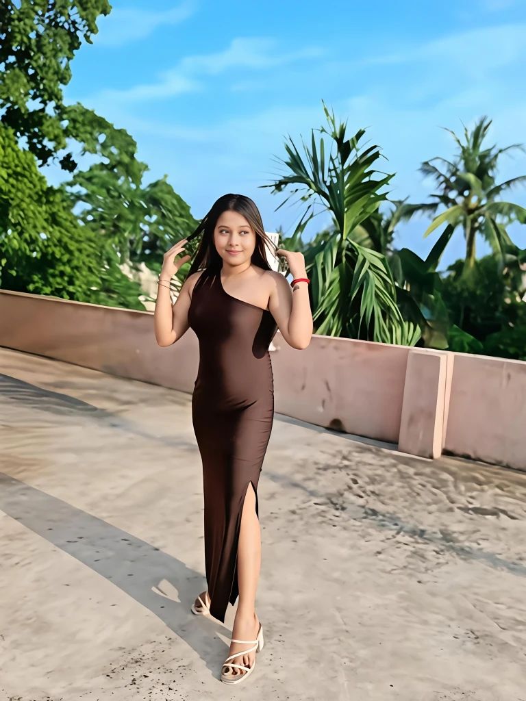 Chubby Escort in Kolkata Ishita standing on a rooftop in a sleeveless brown dress with slit